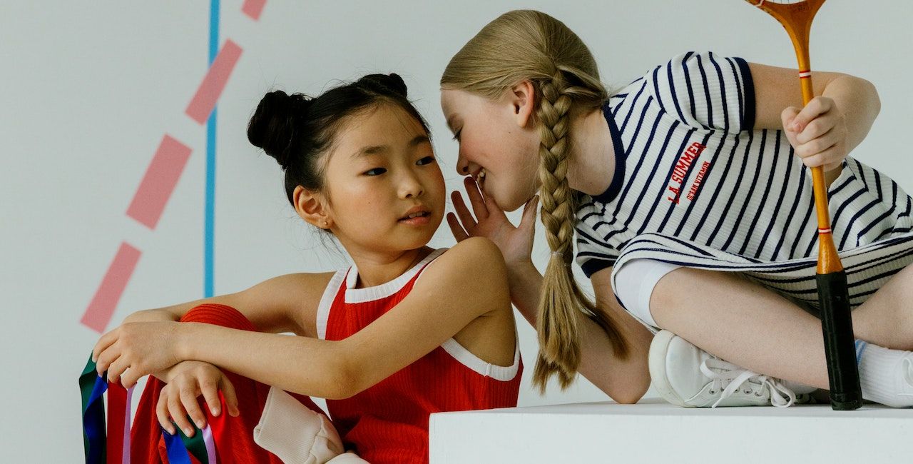 Kids whispering while playing sports.